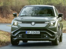 Design frontal robusto do novo Suzuki Vitara elétrico em ambiente urbano e natural.