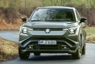 Design frontal robusto do novo Suzuki Vitara elétrico em ambiente urbano e natural.