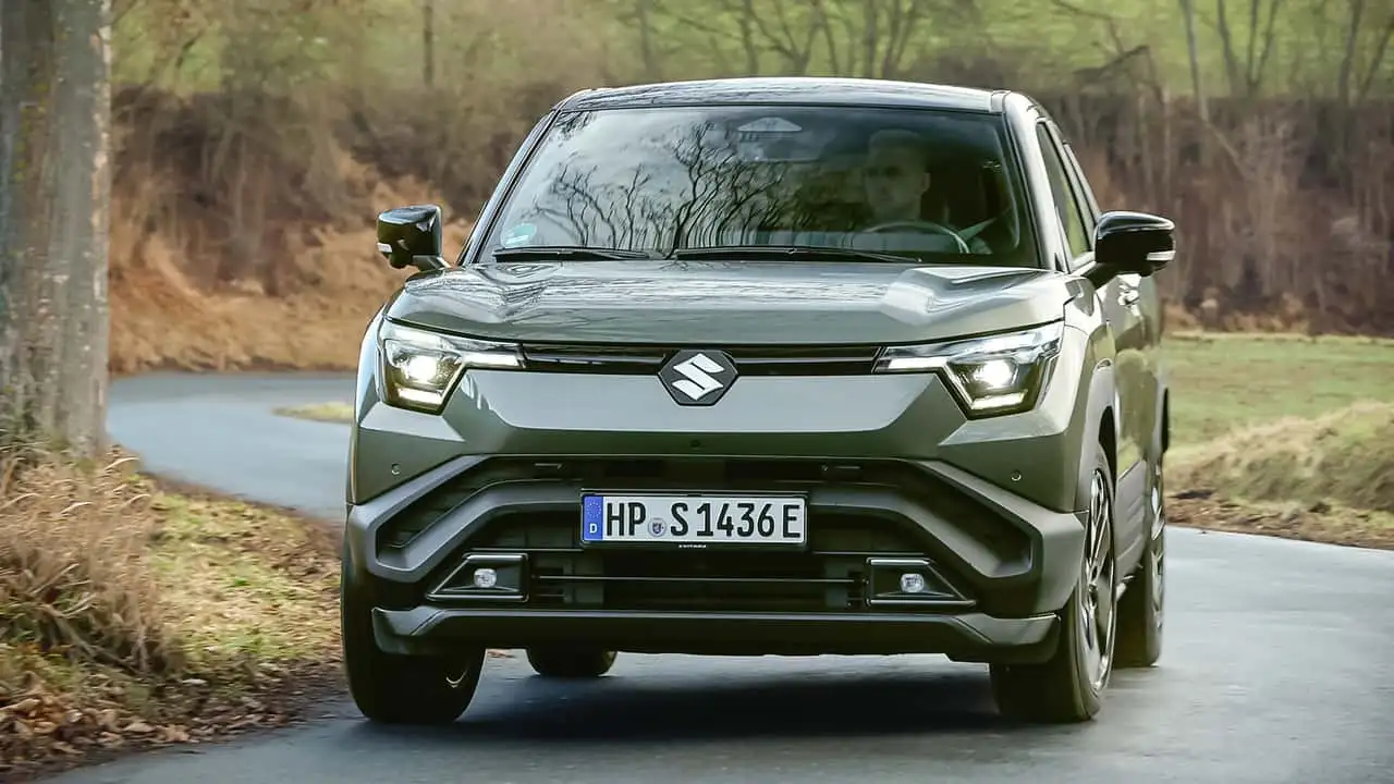 Design frontal robusto do novo Suzuki Vitara elétrico em ambiente urbano e natural.